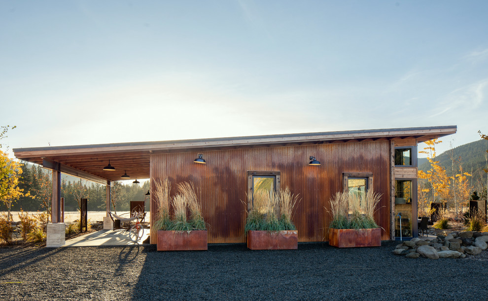 Einstöckiges, Kleines Industrial Einfamilienhaus mit Metallfassade, brauner Fassadenfarbe, Pultdach und Blechdach in Seattle