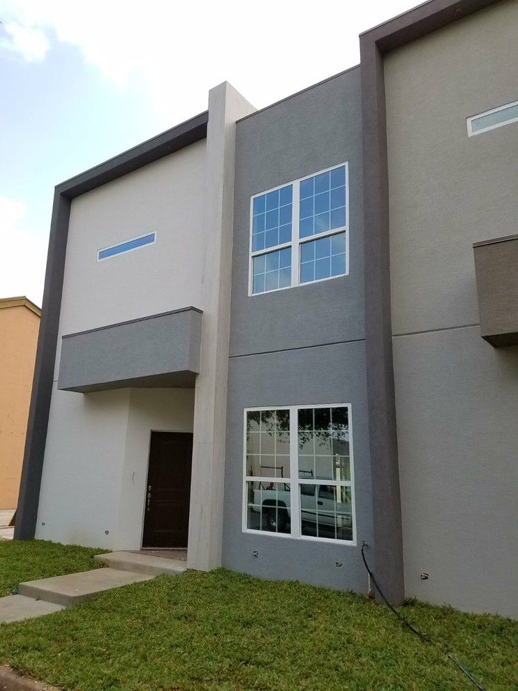 Imagen de fachada de casa pareada gris minimalista de tamaño medio de dos plantas con revestimiento de estuco, tejado plano y techo verde