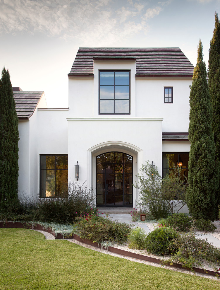 Стильный дизайн: двухэтажный, белый дом в стиле неоклассика (современная классика) с облицовкой из цементной штукатурки и двускатной крышей - последний тренд