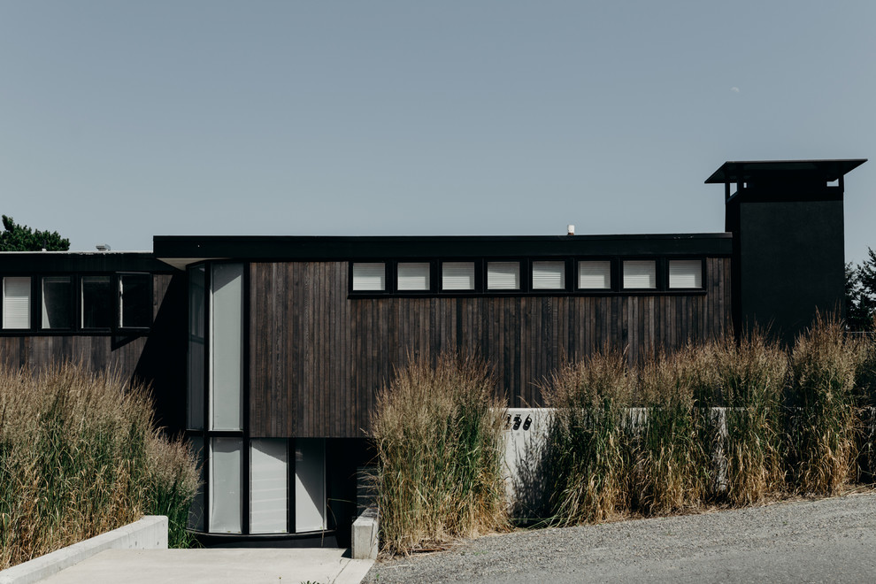 Aménagement d'une façade de maison marron moderne en bois de taille moyenne et à un étage avec un toit plat et un toit en shingle.