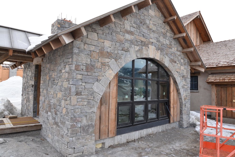 Стильный дизайн: одноэтажный, серый частный загородный дом в стиле фьюжн с облицовкой из камня и металлической крышей - последний тренд