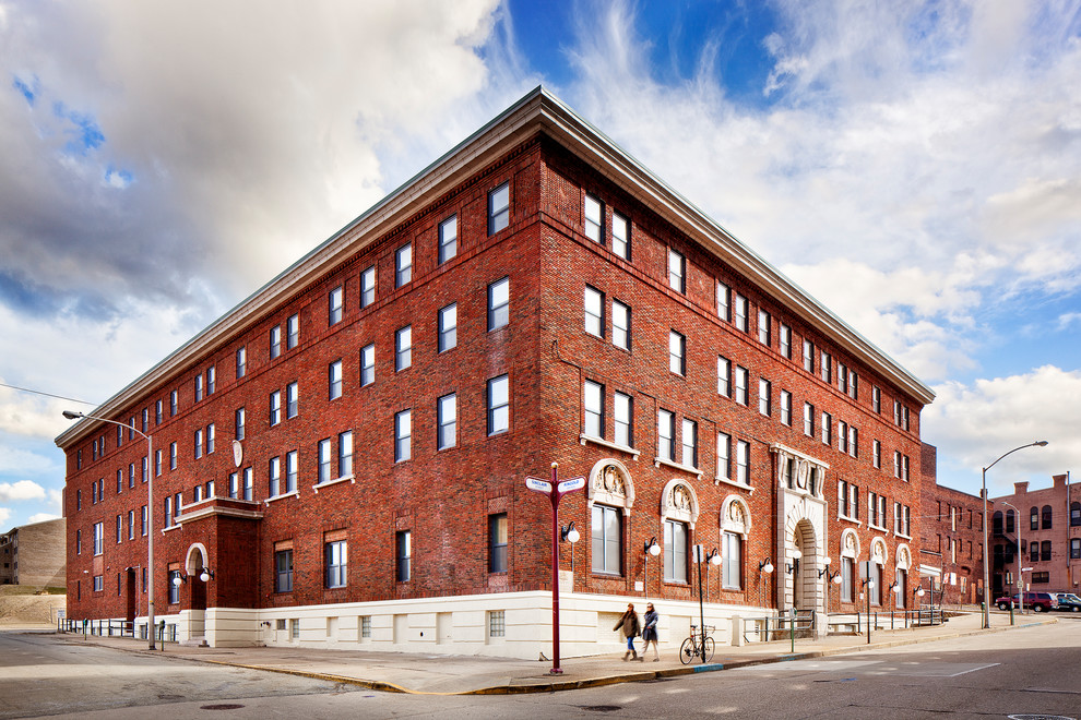 Esempio della facciata di un appartamento ampio rosso industriale a tre piani con rivestimento in mattoni e tetto piano