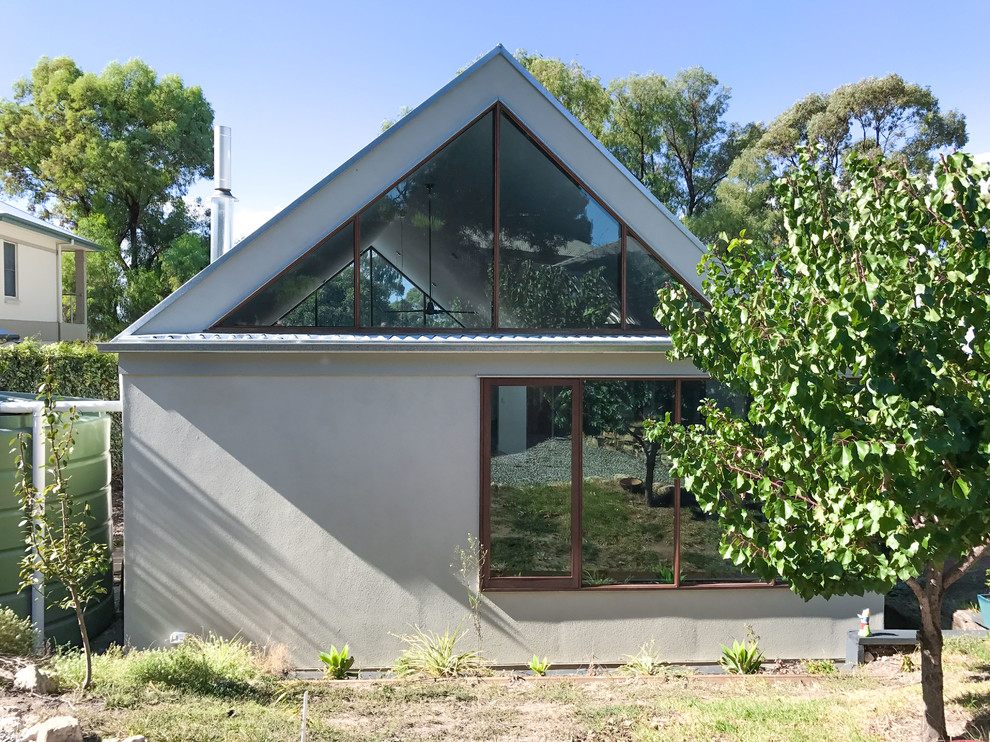 Réalisation d'une façade de maison beige design en brique de taille moyenne et de plain-pied avec un toit à deux pans et un toit en métal.