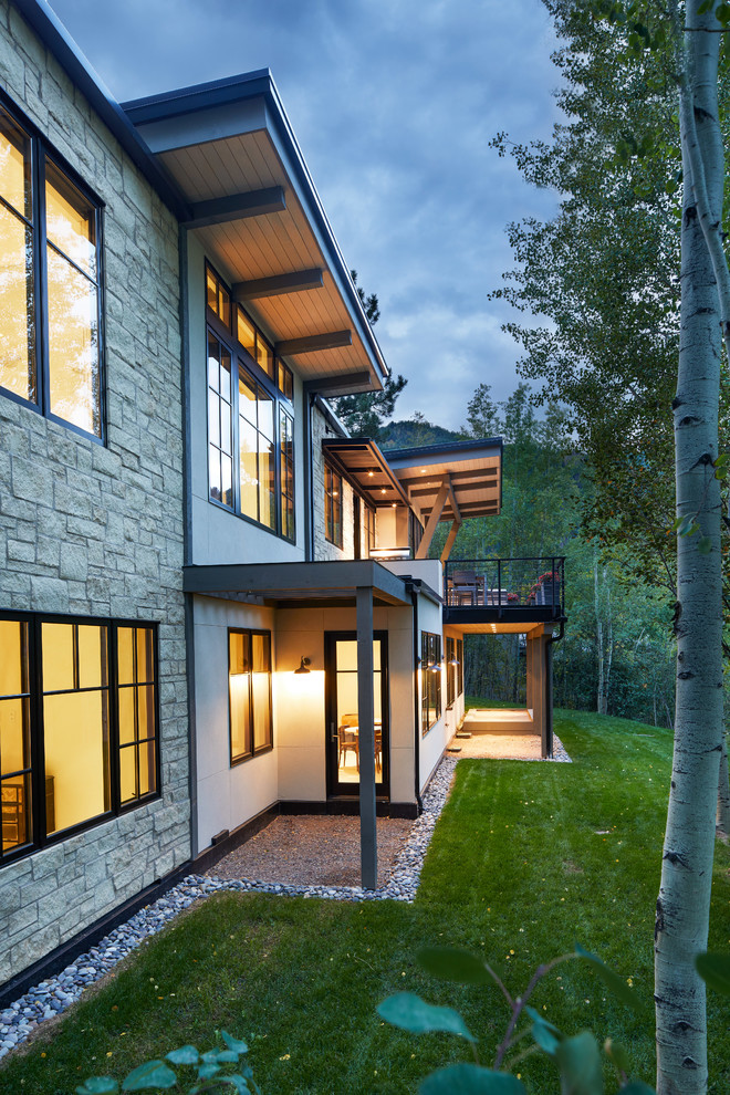 Diseño de fachada de casa beige actual de dos plantas con revestimiento de piedra y tejado de un solo tendido