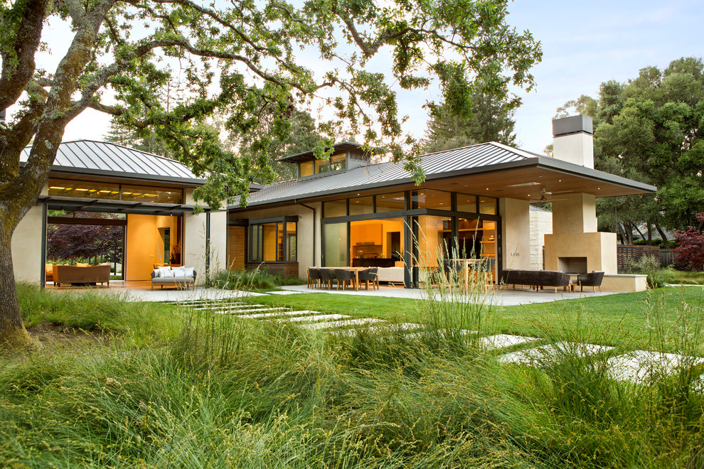 Inspiration pour une grande façade de maison beige design en stuc de plain-pied avec un toit à deux pans et un toit en métal.