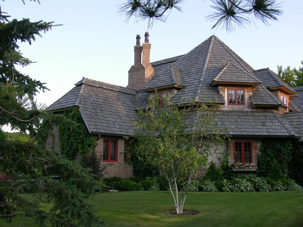 Cette photo montre une grande façade de maison beige montagne en stuc à un étage avec un toit à croupette.