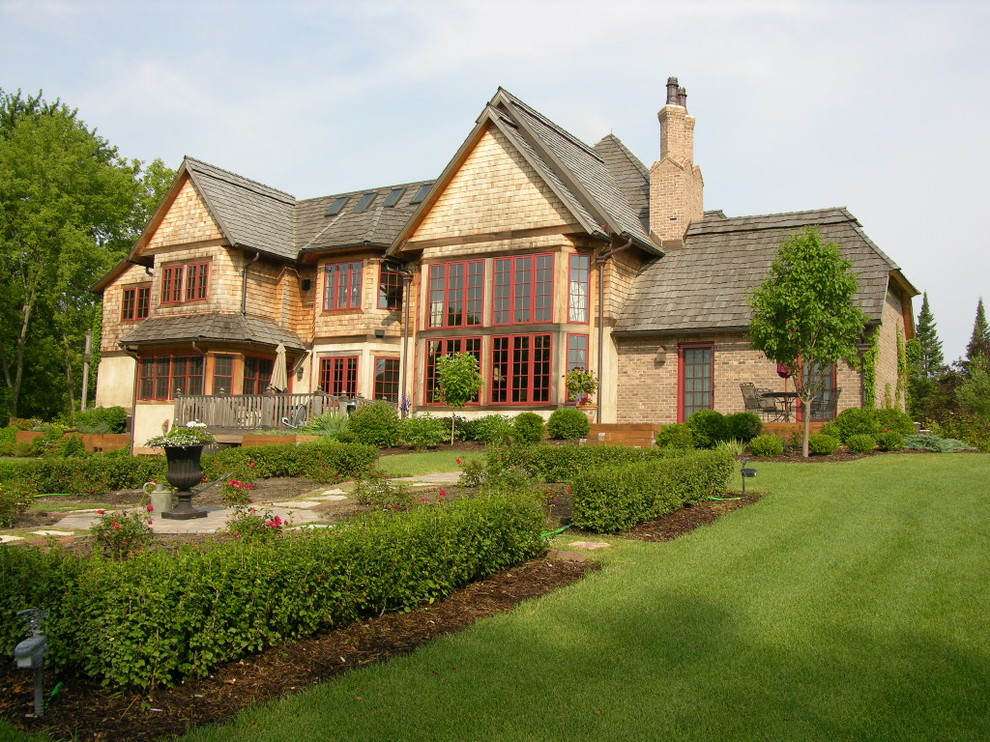 Immagine della facciata di una casa grande beige classica a due piani con rivestimento in stucco e falda a timpano