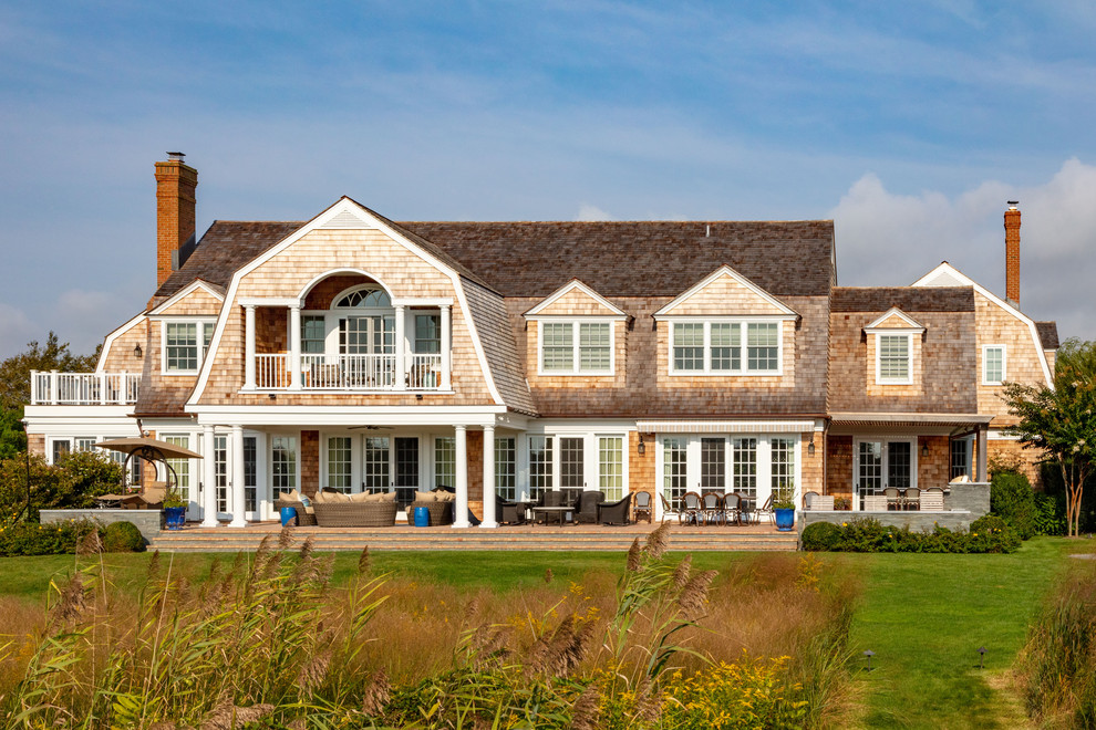 Foto della villa beige stile marinaro a due piani con rivestimento in legno, tetto a mansarda e copertura a scandole