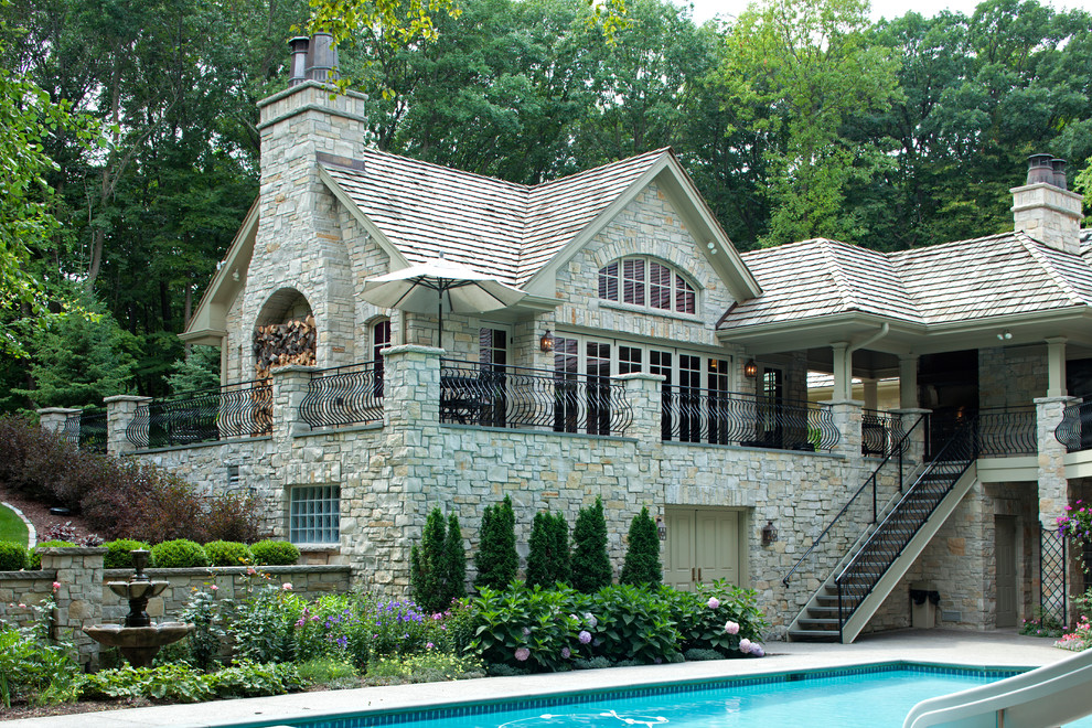 На фото: двухэтажный, серый дом в стиле рустика с облицовкой из камня и двускатной крышей с