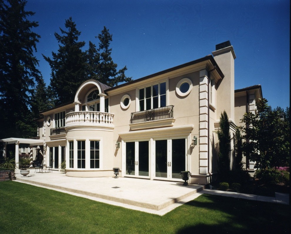 Esempio della villa beige mediterranea a due piani di medie dimensioni con rivestimento in stucco e tetto a padiglione