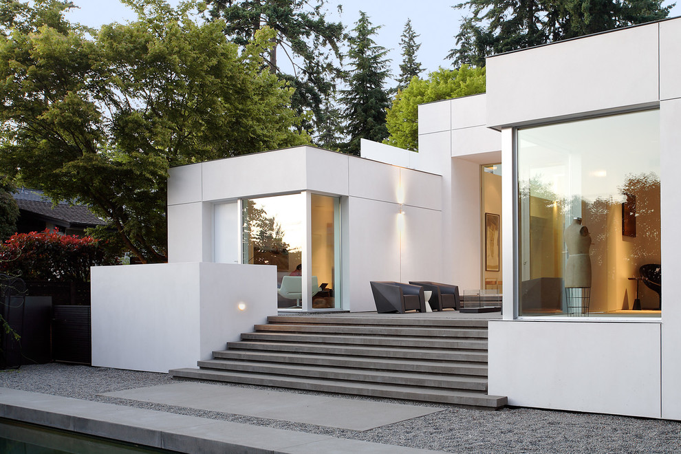 Diseño de fachada blanca moderna con revestimiento de aglomerado de cemento y tejado plano
