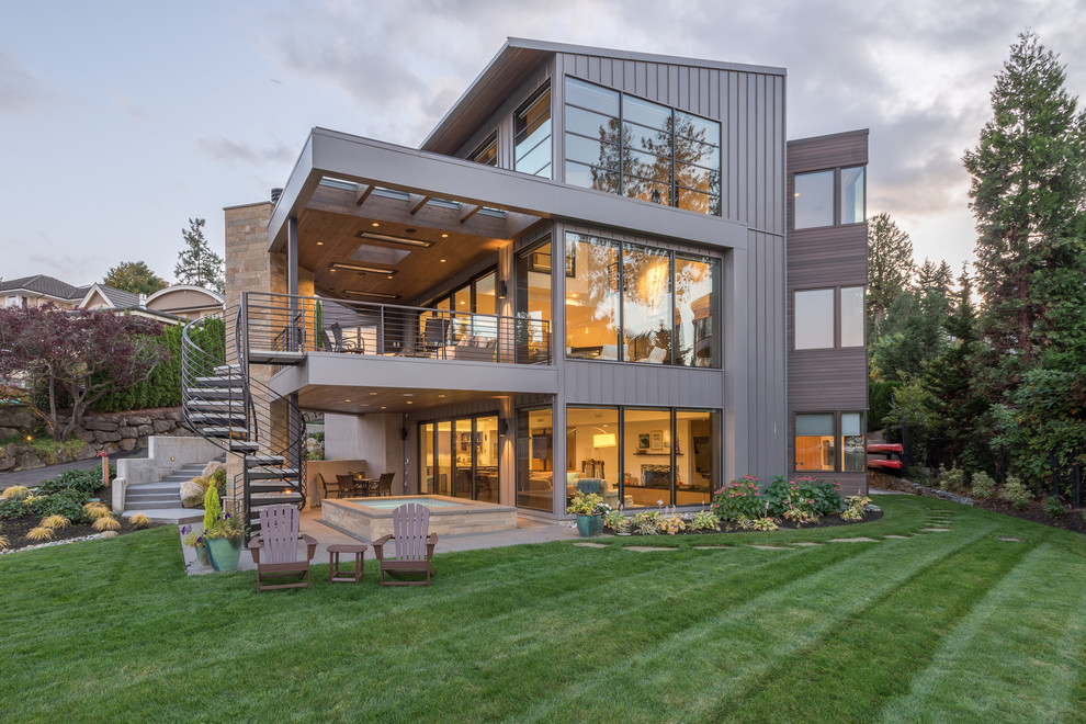 Réalisation d'une grande façade de maison grise et métallique design à deux étages et plus avec un toit en appentis et un toit en métal.
