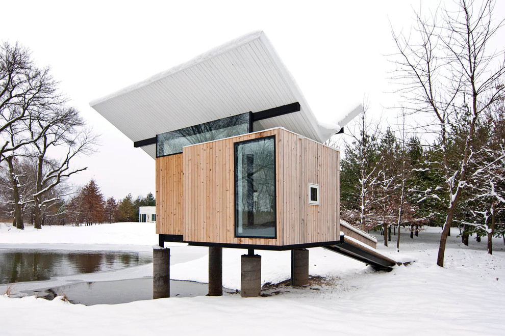 На фото: маленький, одноэтажный, деревянный, коричневый дом в современном стиле с крышей-бабочкой для на участке и в саду
