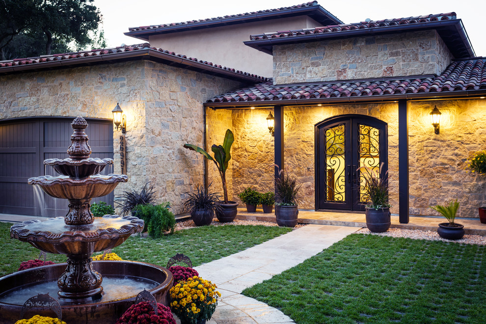 Ejemplo de fachada de casa beige mediterránea grande de dos plantas con revestimientos combinados y tejado a cuatro aguas