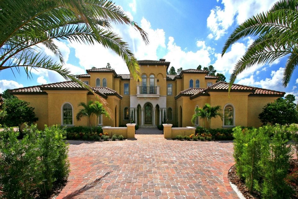 Inspiration for a large mediterranean yellow two-story stucco house exterior remodel in Orlando with a hip roof and a tile roof