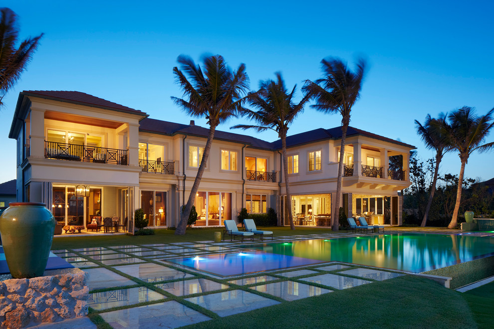 This is an example of a beige mediterranean two floor house exterior in Miami with a hip roof.