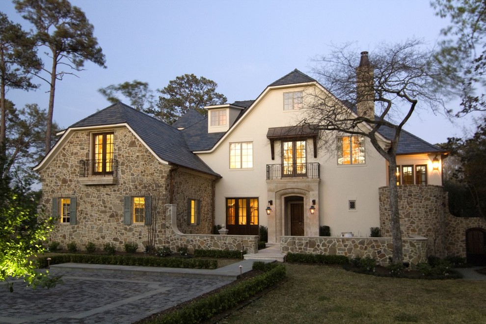 This is an example of a large mediterranean house exterior in Houston with three floors, stone cladding and a half-hip roof.