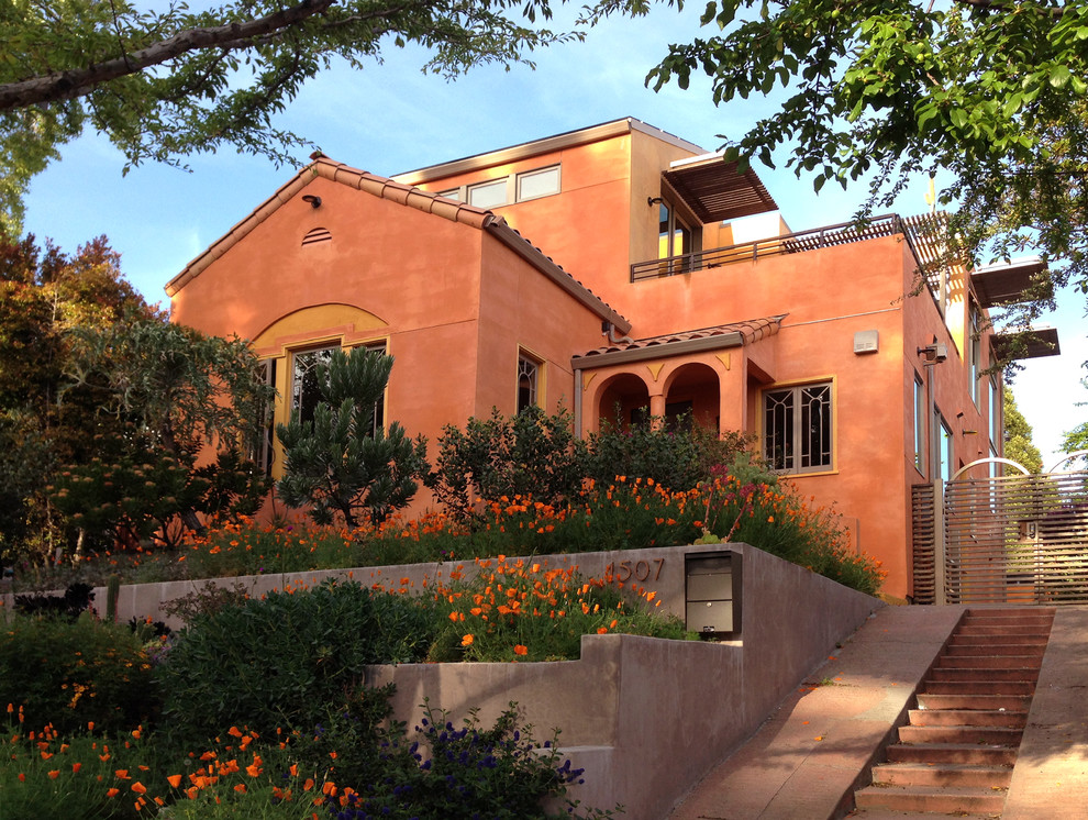 Cette image montre une grande façade de maison marron méditerranéenne en stuc à un étage avec un toit à deux pans.
