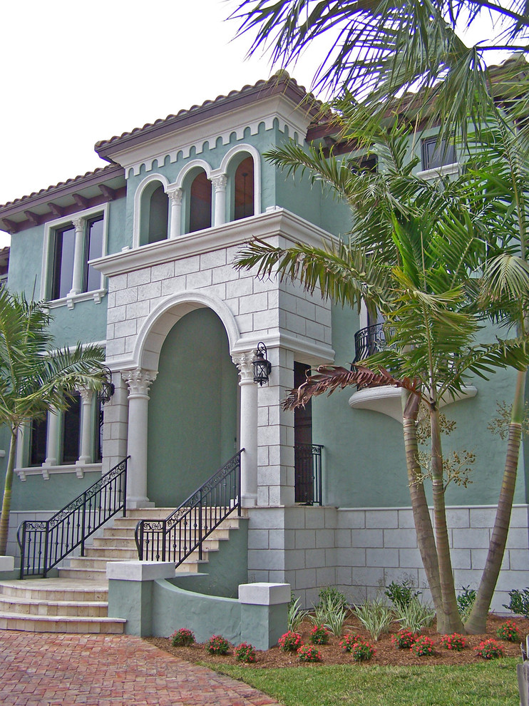 Imagen de fachada verde mediterránea grande de dos plantas con revestimiento de estuco y tejado a cuatro aguas