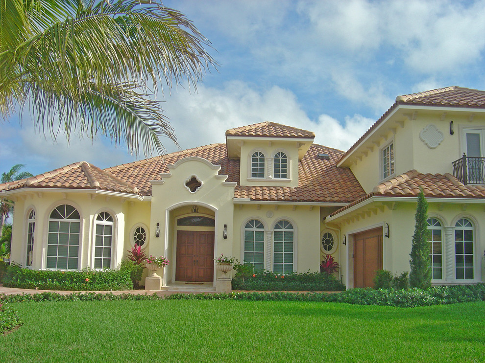Large and beige mediterranean two floor render house exterior in Miami with a hip roof.