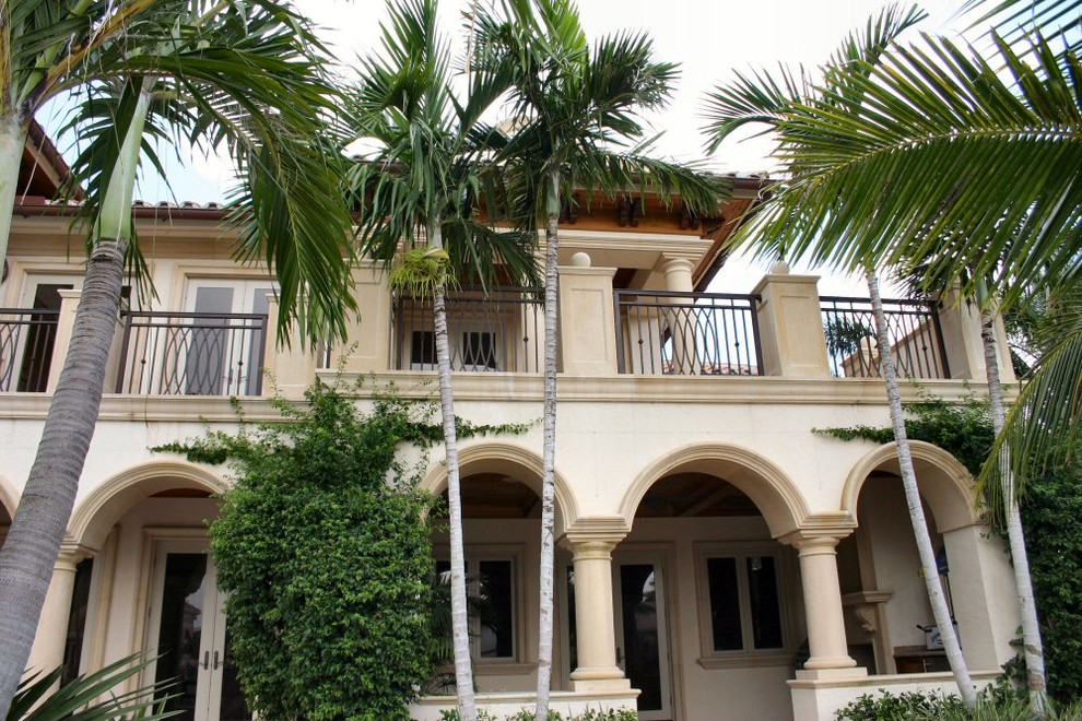 Aménagement d'une grande façade de maison beige méditerranéenne en stuc à un étage.