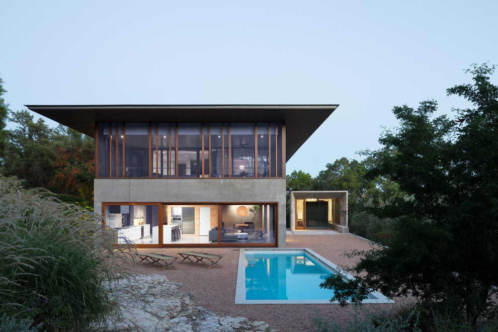 Réalisation d'une façade de maison grise minimaliste en béton à un étage avec un toit plat.