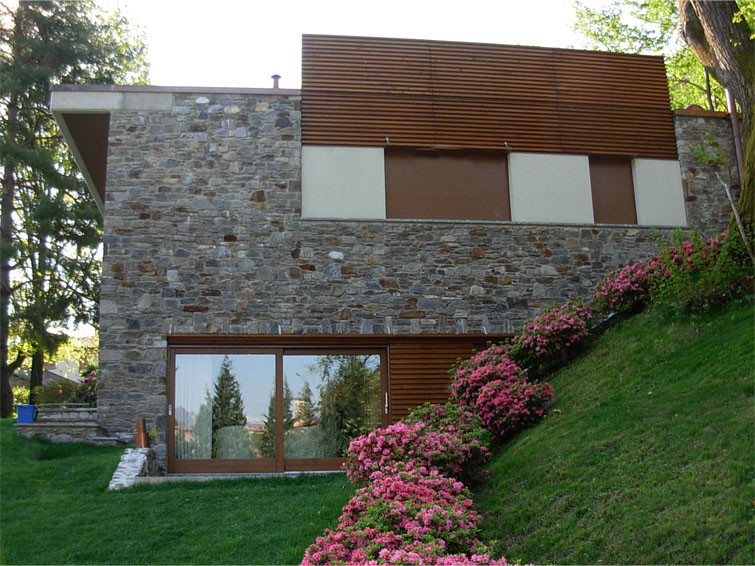 Réalisation d'une très grande façade de maison marron minimaliste en pierre à un étage avec un toit plat.