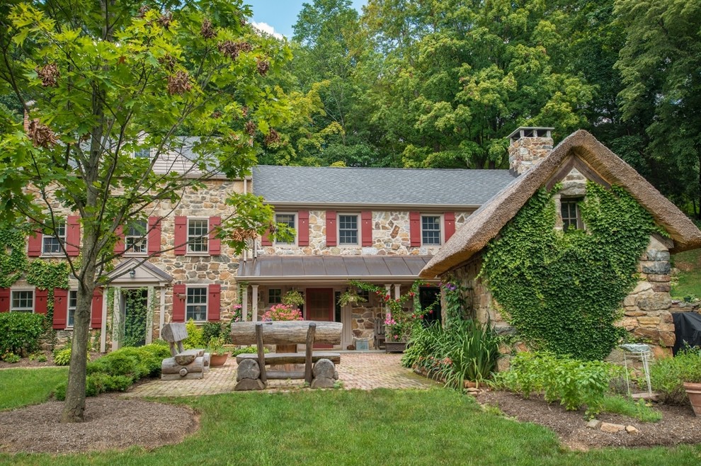 Large rustic two-story stone gable roof idea in New York