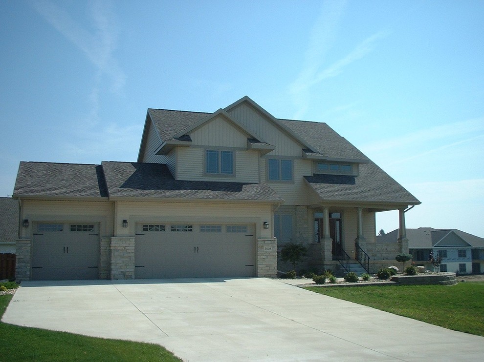 Пример оригинального дизайна: двухэтажный, бежевый, большой дом в стиле кантри с облицовкой из камня и двускатной крышей