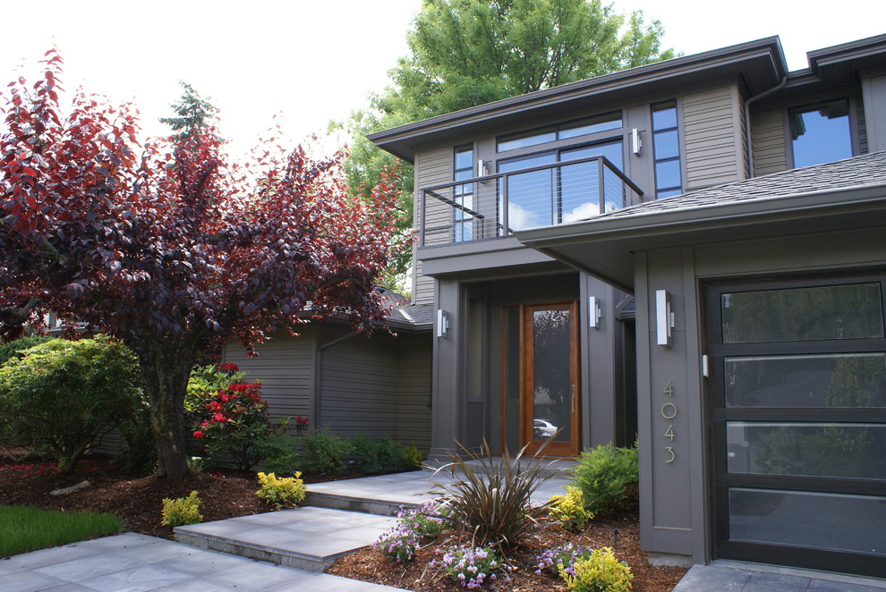 Cette photo montre une grande façade de maison grise tendance en panneau de béton fibré à un étage avec un toit à quatre pans.