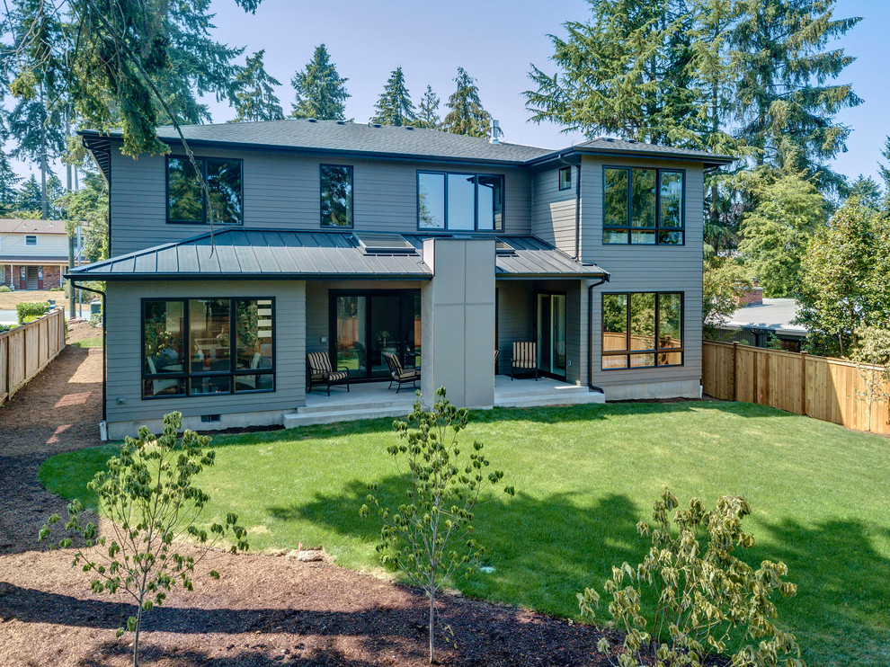 Inspiration pour une grande façade de maison grise design à un étage avec un toit à quatre pans et un toit mixte.