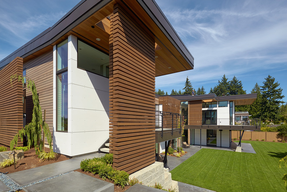 Cette image montre une grande façade de maison multicolore design à un étage avec un revêtement mixte et un toit plat.