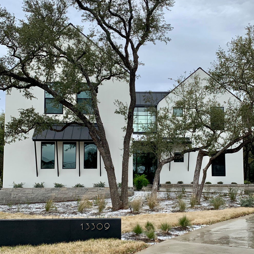 Zweistöckiges Landhausstil Einfamilienhaus mit Putzfassade, weißer Fassadenfarbe, Satteldach und Blechdach in Austin