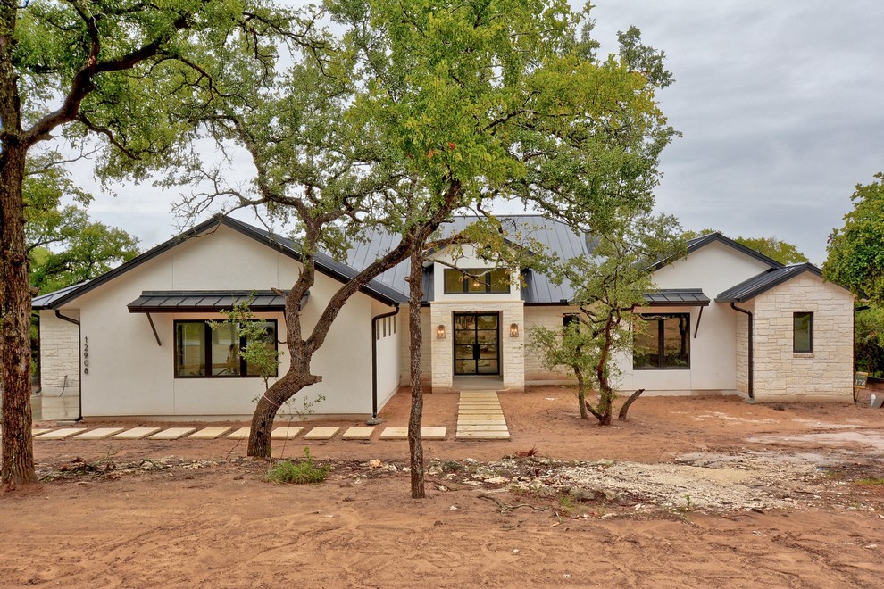 Photo of a white contemporary bungalow render detached house in Austin with a hip roof and a metal roof.