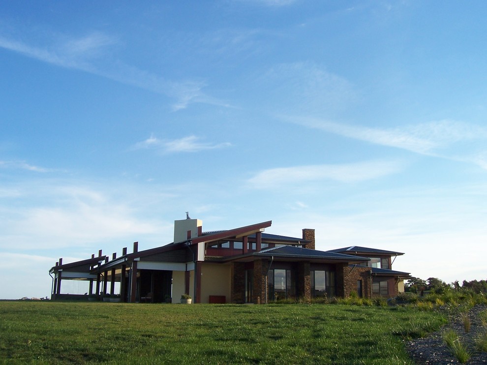 Immagine della villa ampia beige contemporanea a un piano con rivestimento in pietra e copertura in metallo o lamiera