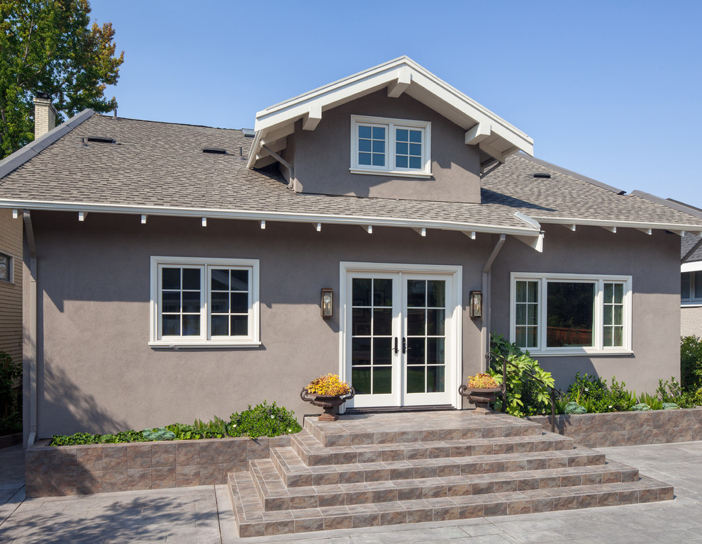 Diseño de fachada de casa gris clásica de tamaño medio de dos plantas con revestimiento de estuco y tejado a dos aguas