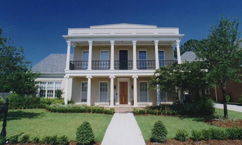 На фото: большой, двухэтажный, бежевый дом в классическом стиле с облицовкой из цементной штукатурки и вальмовой крышей с