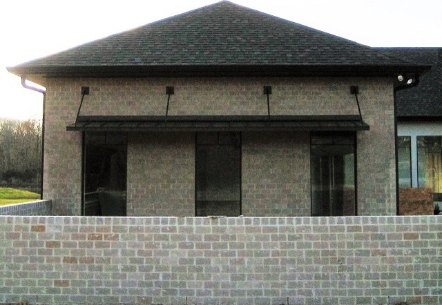 Imagen de fachada de casa beige tradicional de tamaño medio de una planta con revestimiento de ladrillo, tejado a cuatro aguas y tejado de teja de madera