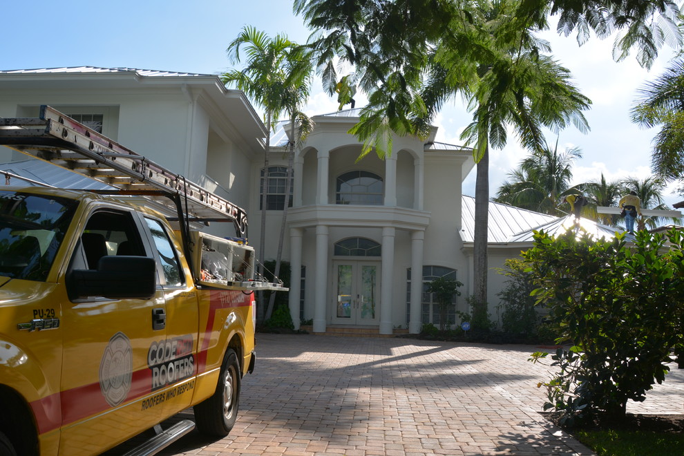 This is an example of an expansive and white mediterranean two floor render detached house in Orlando with a metal roof.
