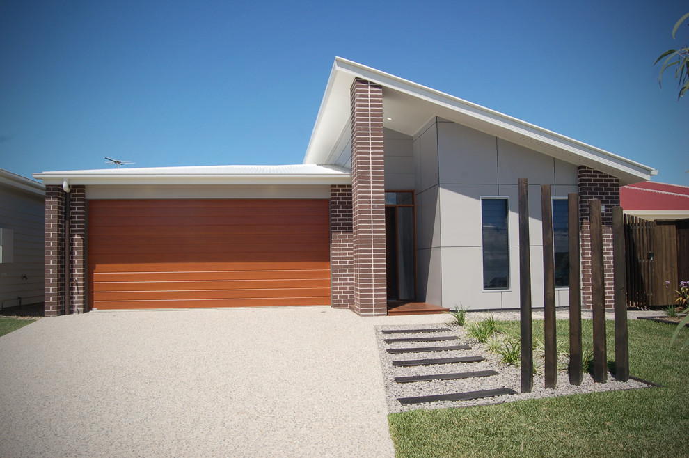 Immagine della facciata di una casa piccola grigia contemporanea a un piano con rivestimento in mattoni e copertura in metallo o lamiera