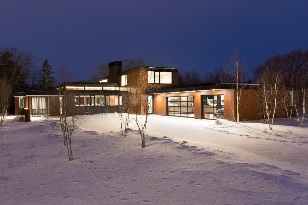 Foto de fachada de casa marrón moderna grande de dos plantas con revestimiento de madera y tejado plano