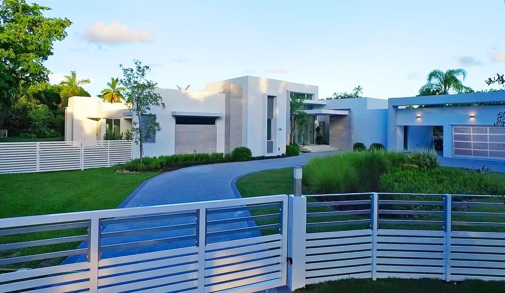 На фото: огромный, одноэтажный, белый частный загородный дом в стиле модернизм с облицовкой из бетона и плоской крышей с