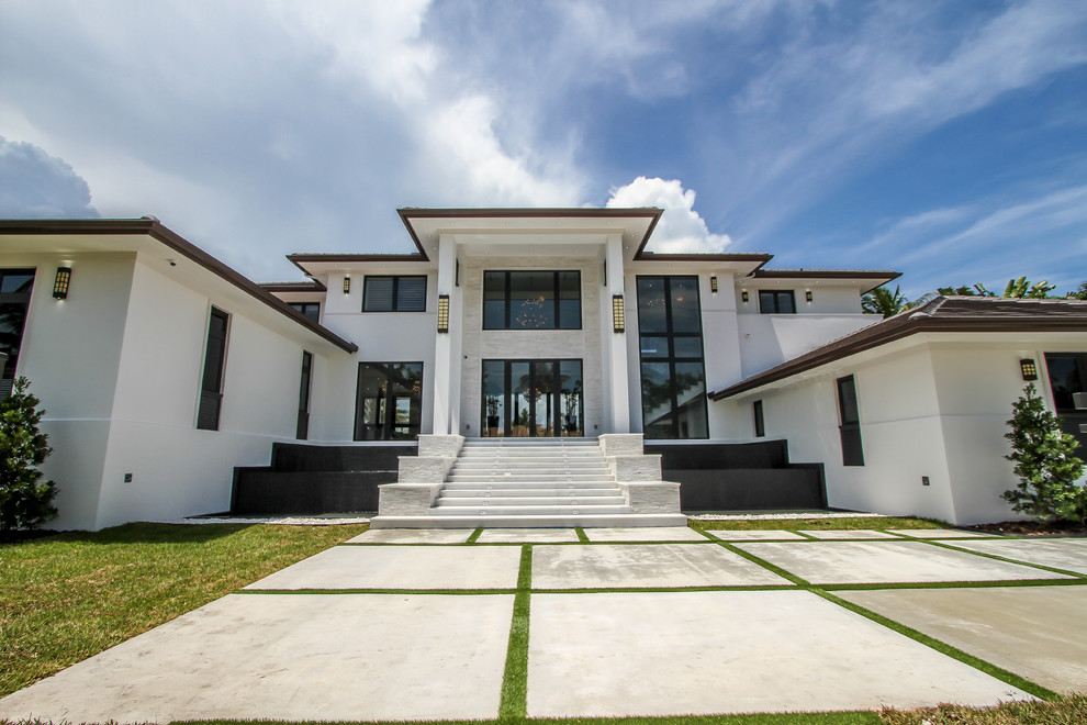 Inspiration for a large modern white two-story stucco exterior home remodel in Miami with a shingle roof