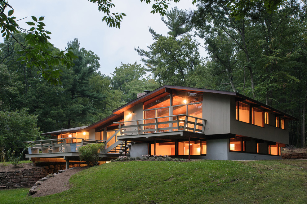 Aménagement d'une façade de maison grise rétro en bois à niveaux décalés avec un toit à deux pans.