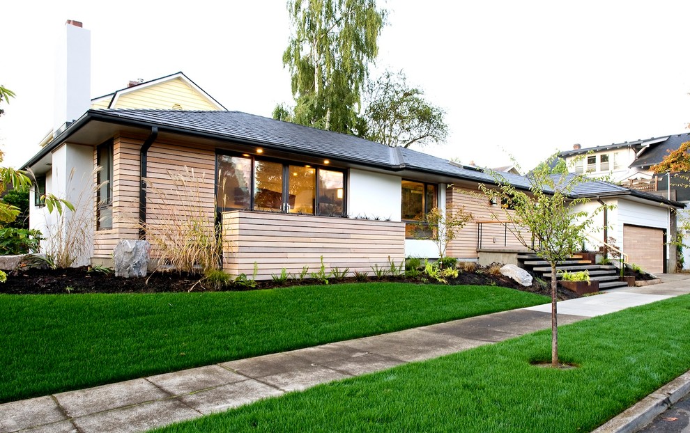 This is an example of a medium sized midcentury bungalow render house exterior in Portland.