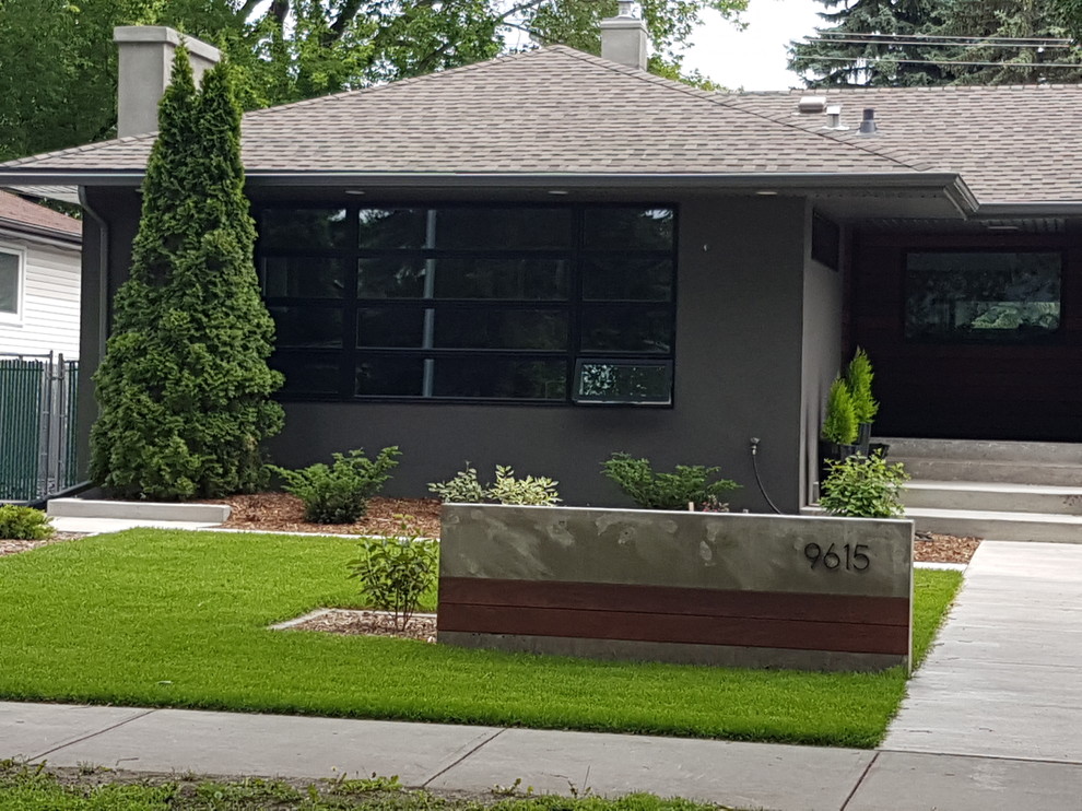 Example of a mid-sized 1960s gray one-story concrete house exterior design in Edmonton with a hip roof and a shingle roof