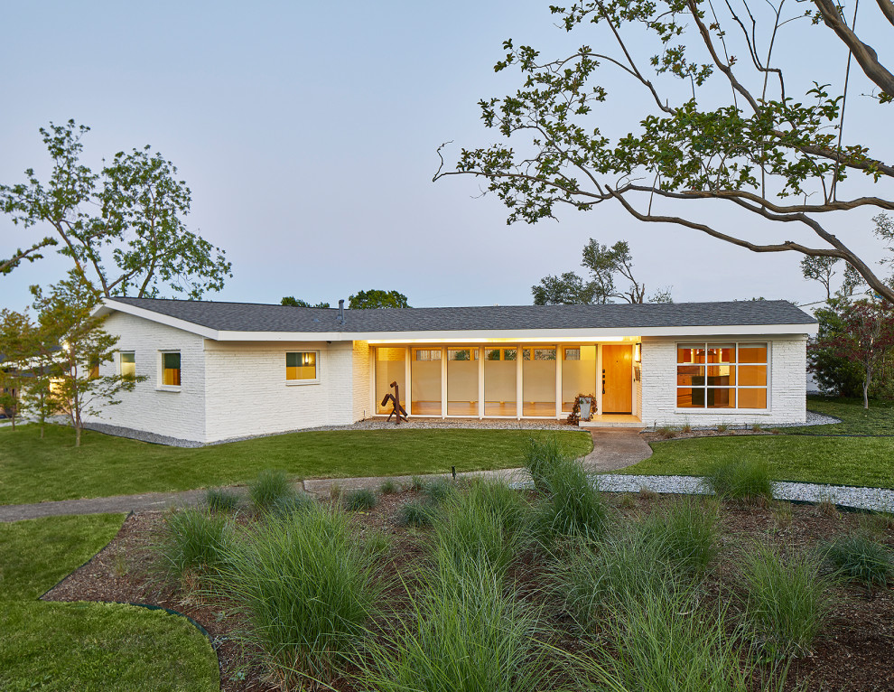 This is an example of a medium sized and white midcentury bungalow painted brick detached house in Dallas with a pitched roof and a shingle roof.