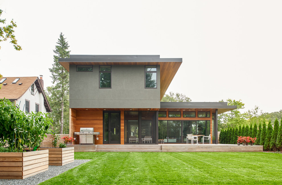 This is an example of a medium sized and gey midcentury two floor house exterior in Minneapolis with mixed cladding and a flat roof.
