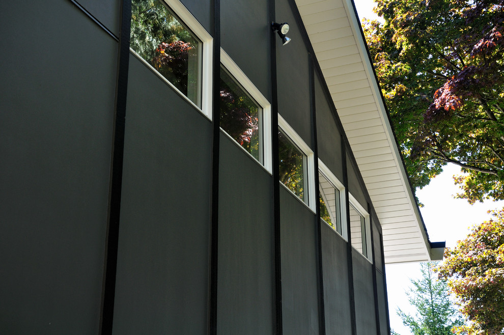 Réalisation d'une façade de maison grise vintage en panneau de béton fibré à un étage et de taille moyenne avec un toit à deux pans et un toit en shingle.