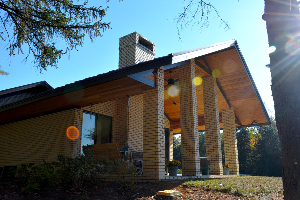 This is an example of a large and white midcentury bungalow brick house exterior in Charlotte with a pitched roof.